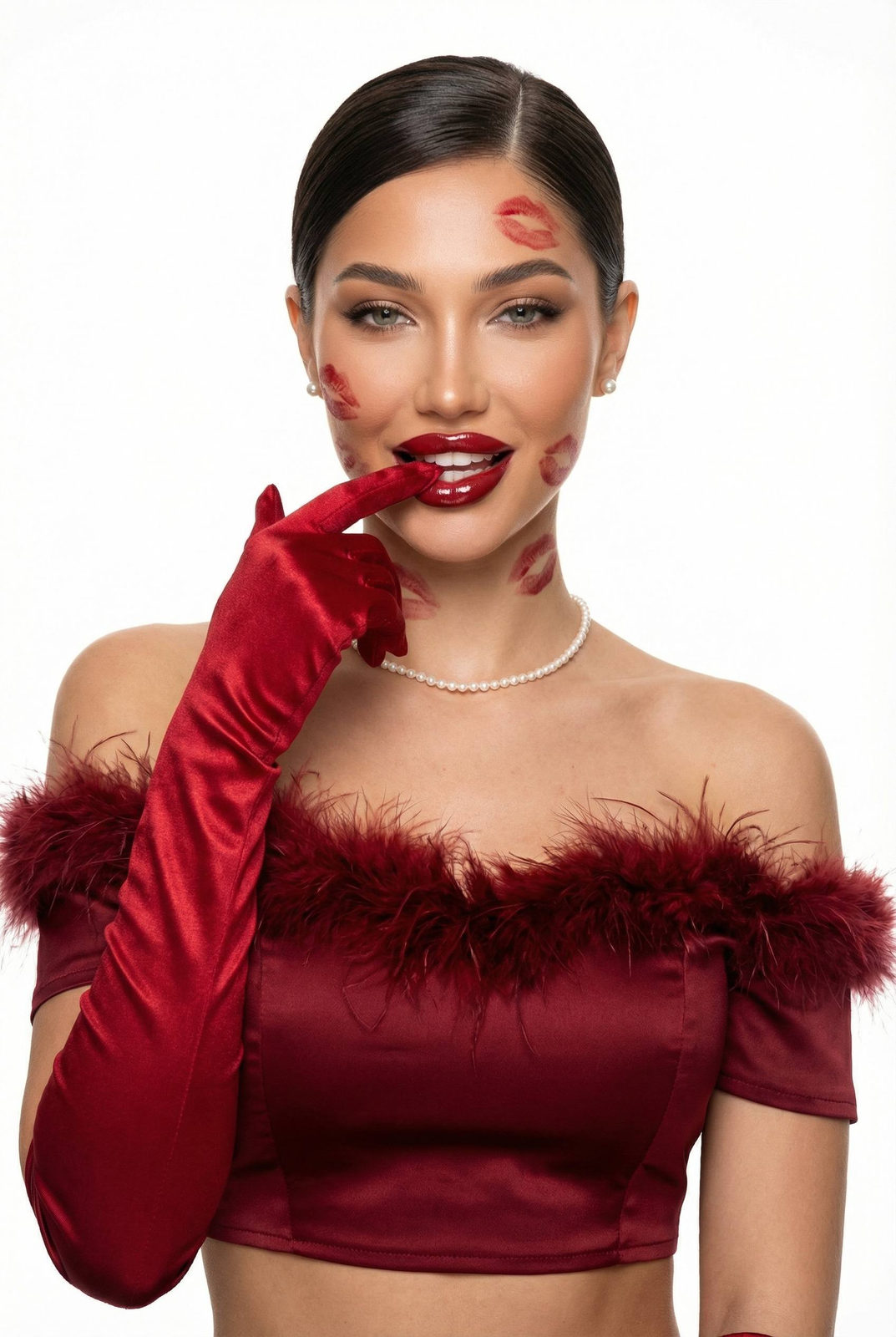 A model in a dark red satin cropped top, playfully touching her lips with a red glove against a pure studio background.