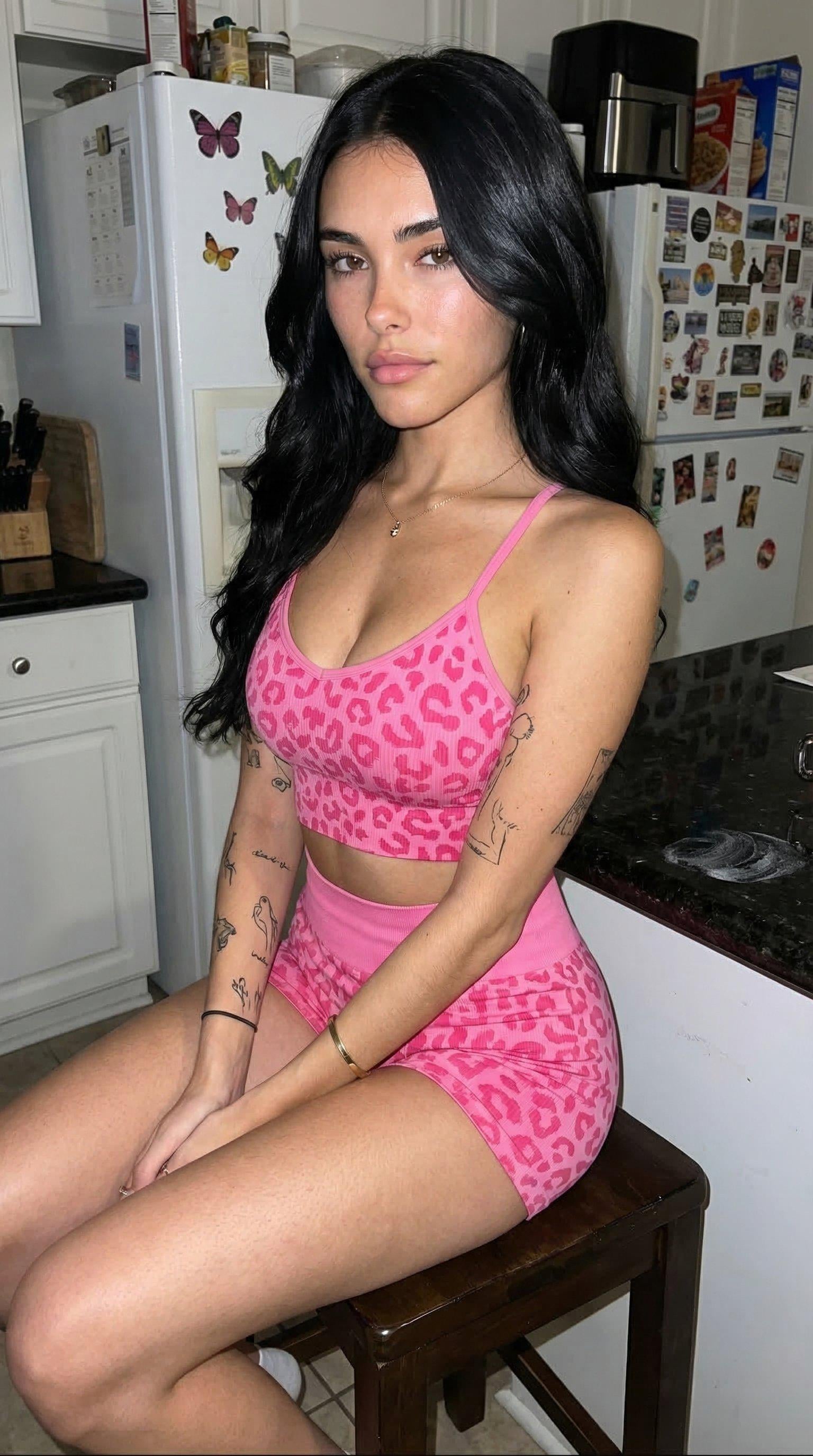 A fit Australian woman in a leopard crop top sitting sideways on a dark stool in a casual kitchen setting, slight smirk, vibrant colors.