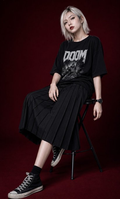 A woman seated on a black folding stool, angled right, with low key maroon background, showcasing subtle beauty lighting.