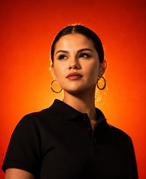 A medium close-up portrait of a person wearing large gold hoop earrings and a black polo shirt against an orange gradient background.