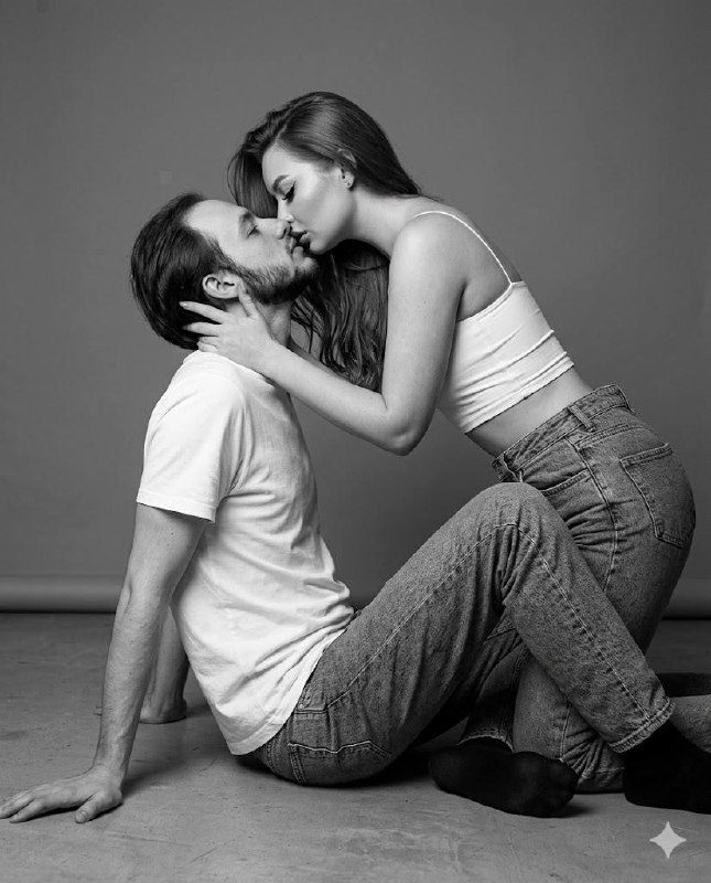 A man in simple socks leans back on the floor as a woman tenderly kisses him, captured in hyper-realistic black and white.