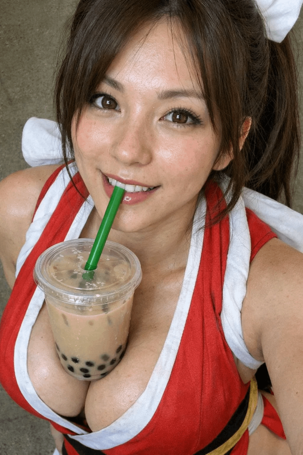 Anime-style portrait of Mai Shiranui with bubble tea in a high angle, playful expression and long brown hair.
