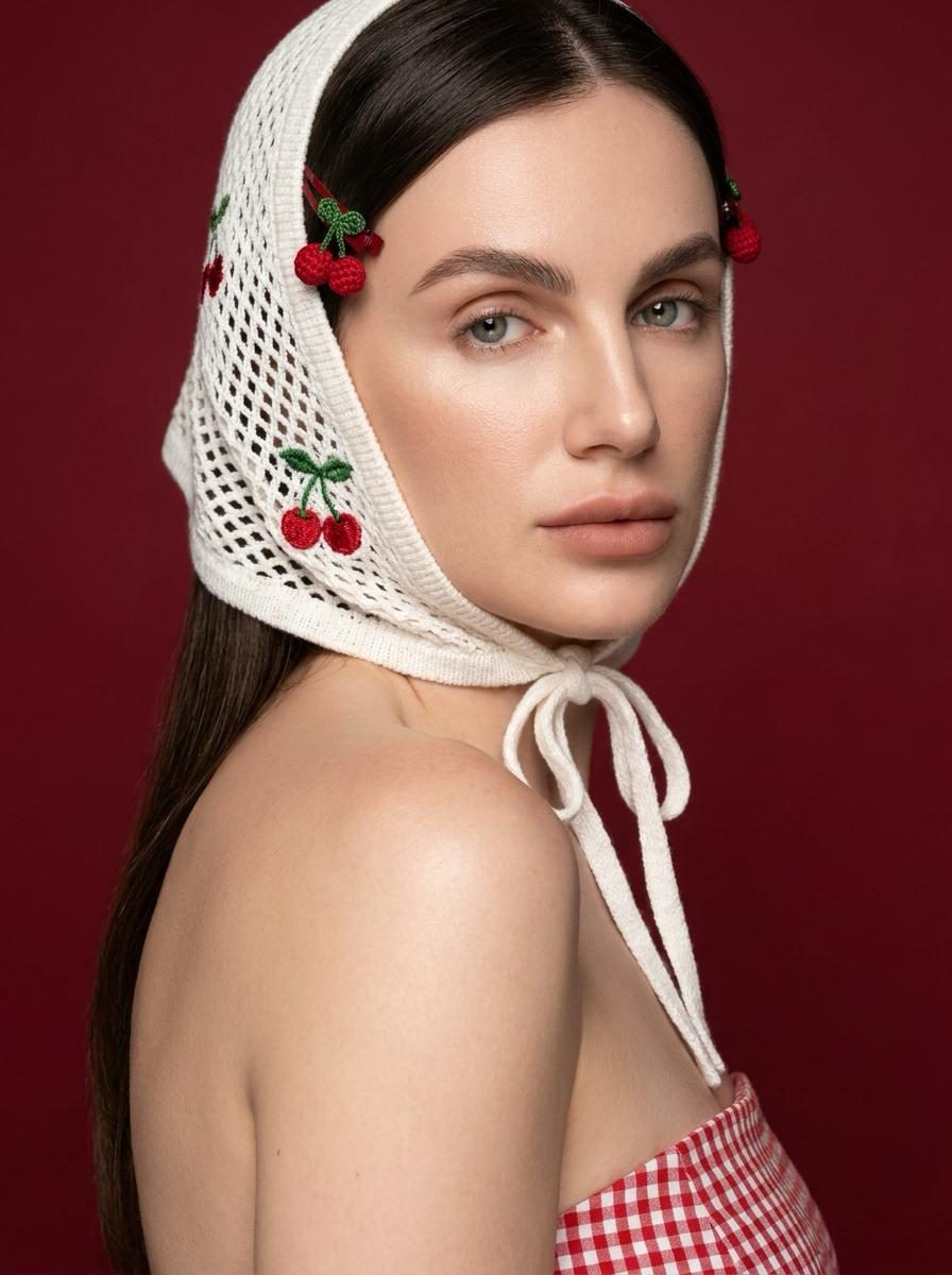 Close-up studio portrait of a woman with a cherry-patterned dress, looking into the camera, emphasizing delicate details and smooth skin.